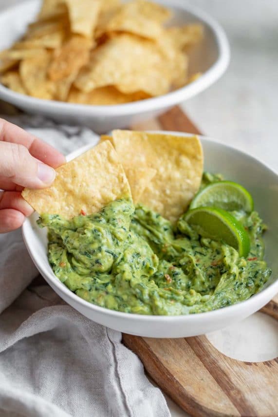 Dipping chips into a bowl of Kale Guacamole