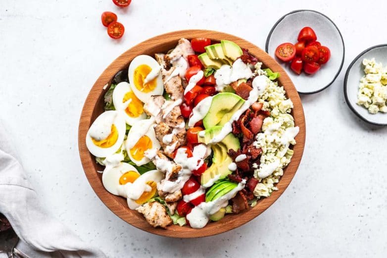 Preparing a bowl of Cobb Salad with Ranch