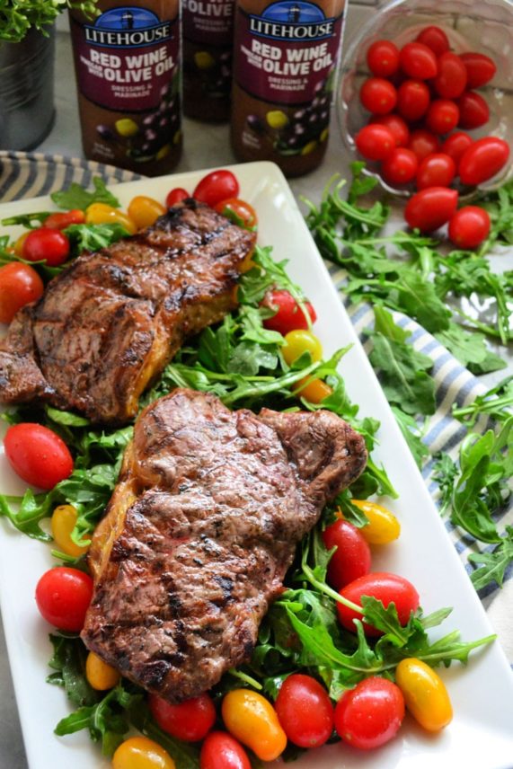Red Wine Vinegar and Olive Oil Steaks with Arugula and Tomato Salad ready to eat