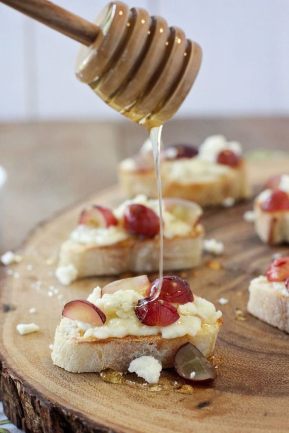 Drizzling honey over Gorgonzola, Grape and Honey Crostini